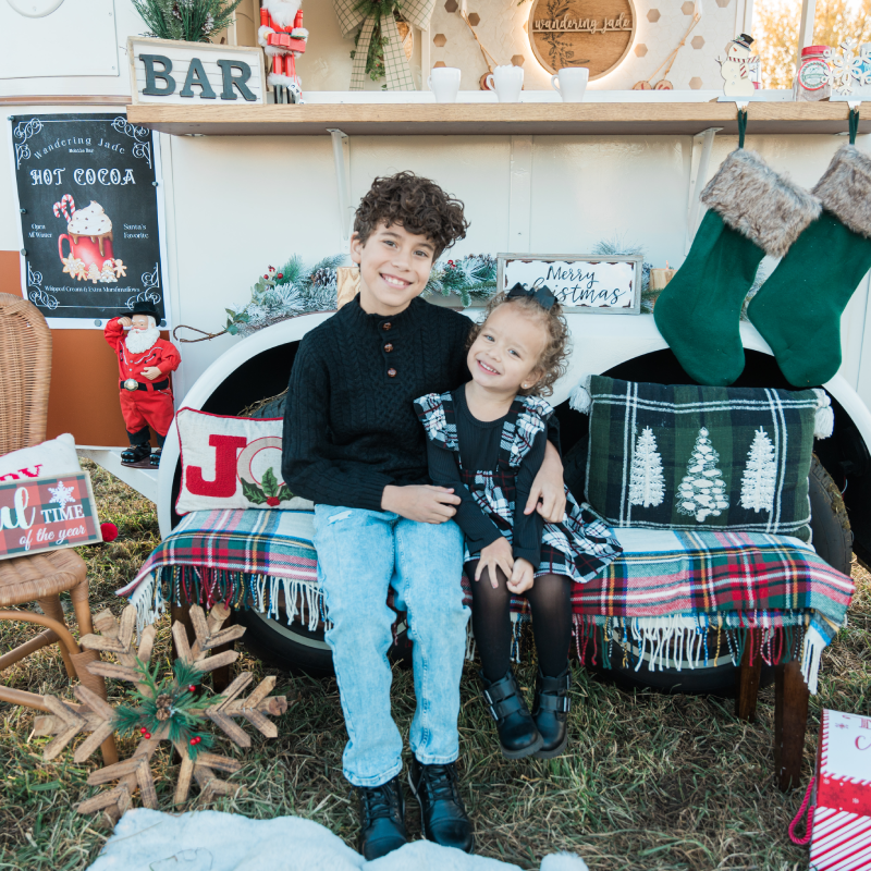 Photo of two kids in front of the Wandering Jade Trailer with Christmas Decorations.